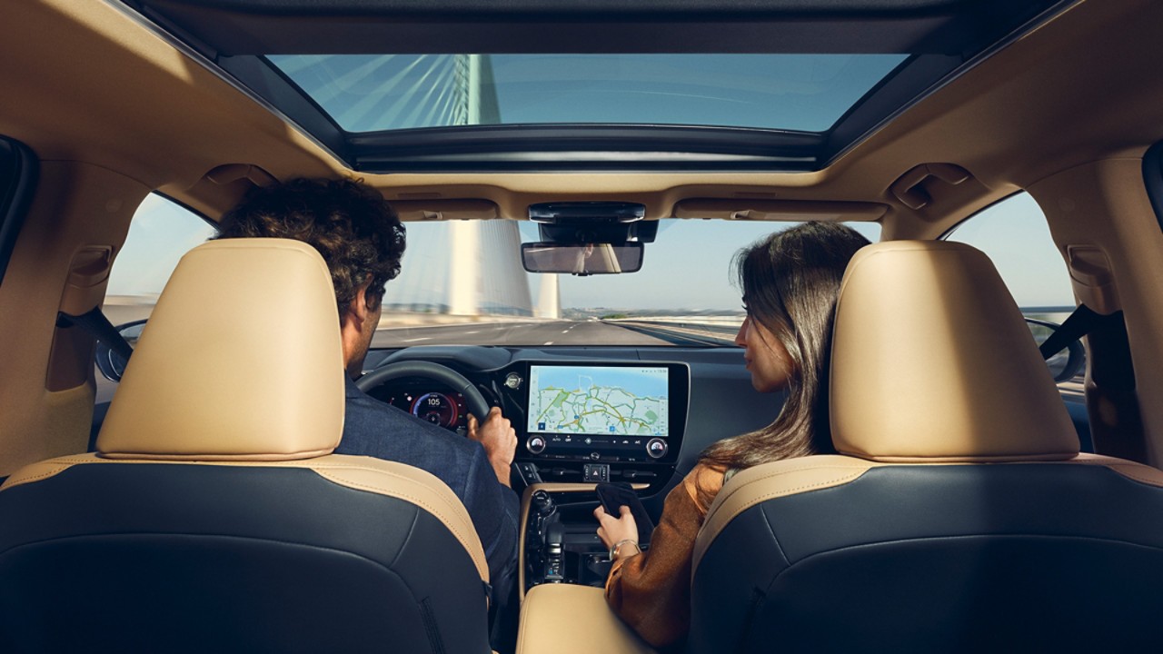 A man and woman driving a Lexus across a bridge