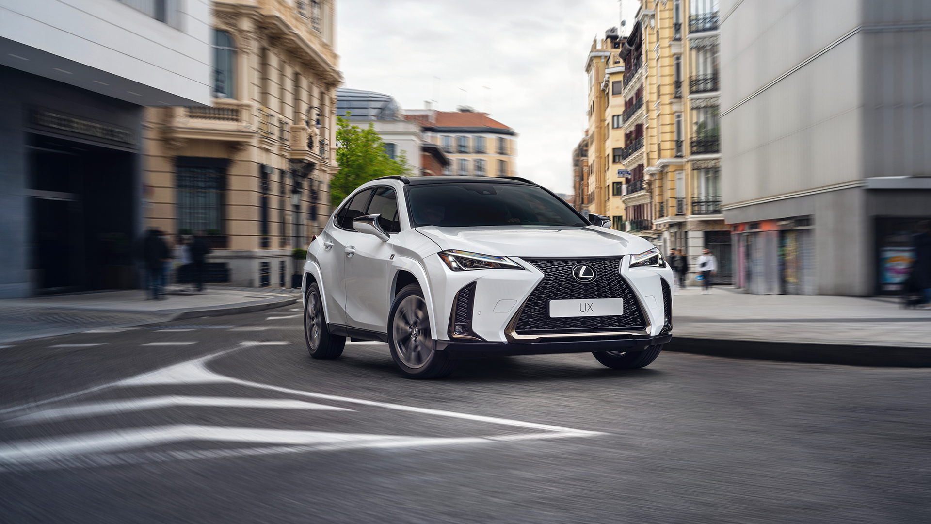 A Lexus UX driving round a corner in a town